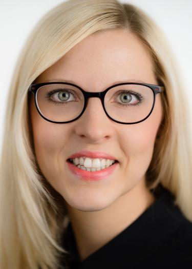 Blonde Frau mit schwarzer Brille in schwarzer Bluse